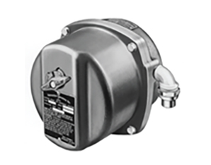 A black and white image of a round, industrial metal device with a protruding lever and a label on its front, and a pipe connector attached to the side.